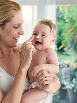 Ein zärtlicher Moment zwischen einer Mutter und ihrem Baby, in dem die Mutter spielerisch die Nase des Babys berührt.