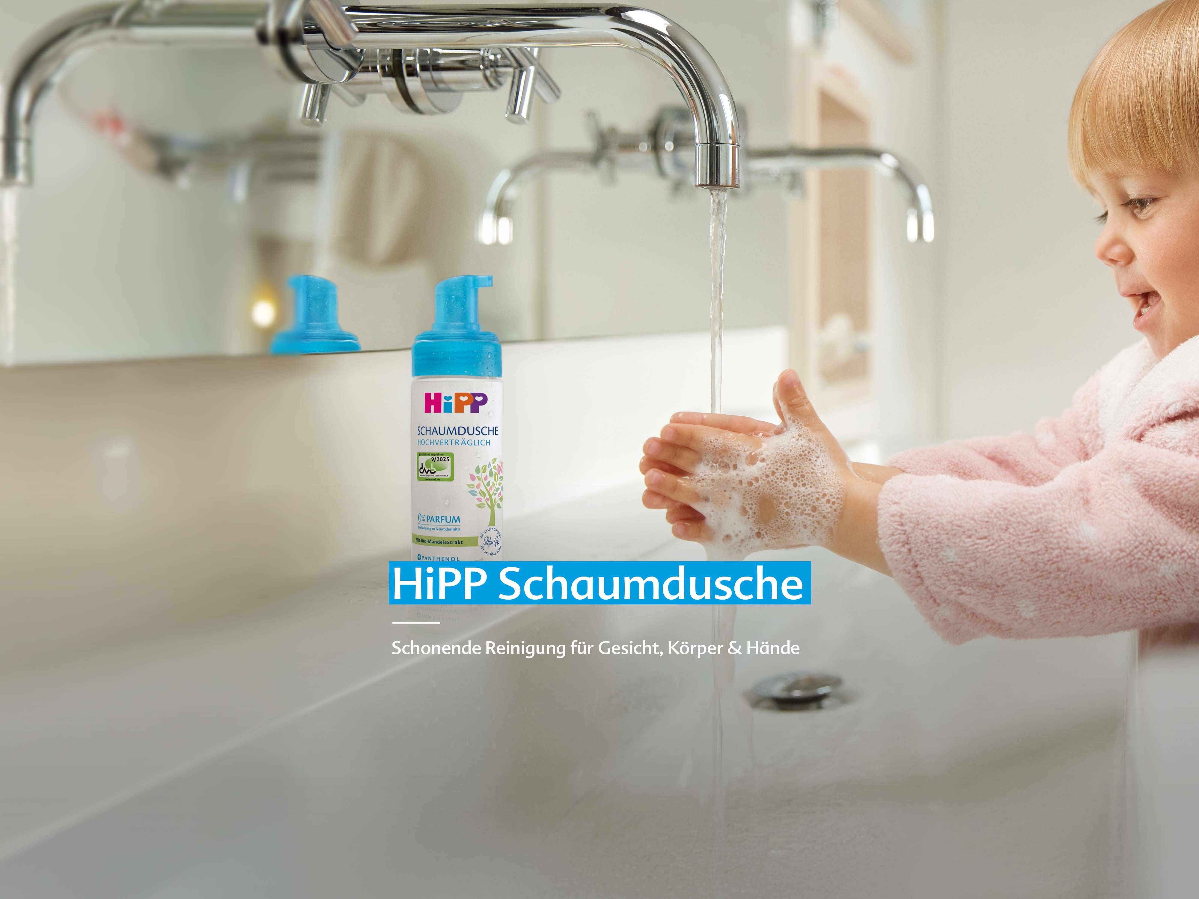 Kind wäscht Hände unter fließendem Wasser neben einer Flasche HiPP Schaumdusche auf dem Waschbecken
