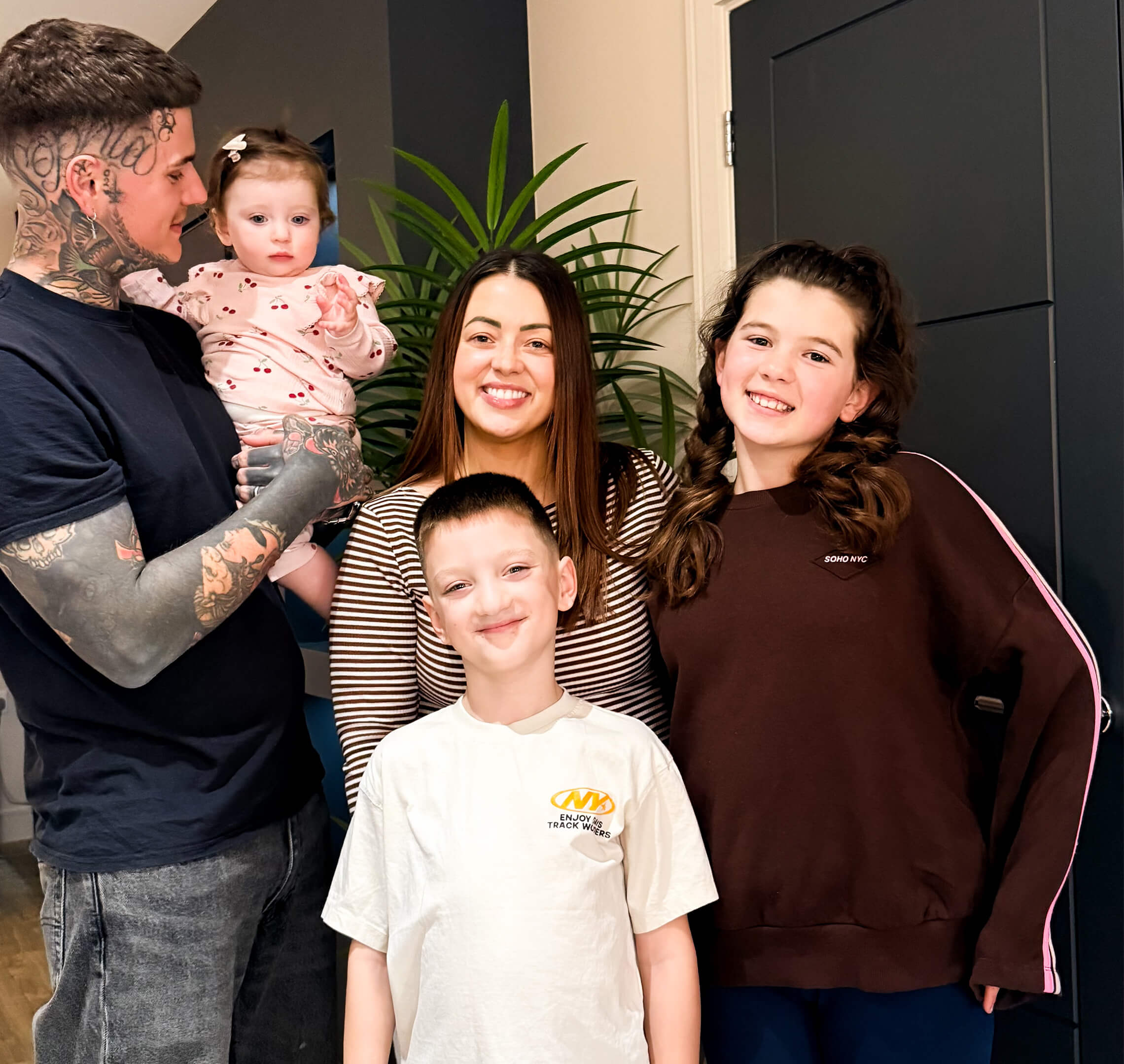 Connor and Charlotte smiling at home with their three young children, capturing a happy family moment