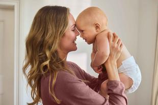 Mutter hält ihr lachendes Baby auf Augenhöhe, Stirn an Stirn – inniger, vertrauensvoller Moment im Alltag.