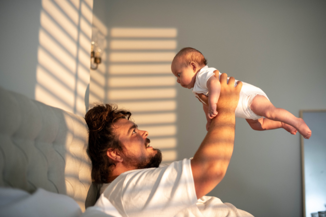 Dad playing with newborn baby infront of window