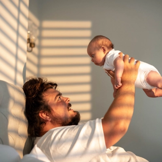 Dad playing with newborn baby infront of window