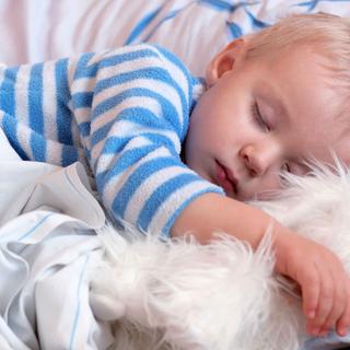 Ein schlafender Junge umarmt ein Kuscheltier.