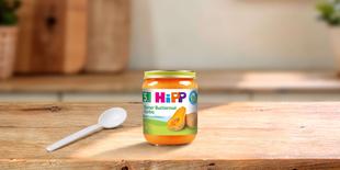HiPP Bio-Gläschen „Reiner Butternut Kürbis“ ab dem 5. Monat mit Löffel auf Holztisch in heller Küche