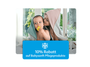 Zwei Kinder mit Handtüchern auf dem Kopf sitzen Rücken an Rücken vor einem Fenster