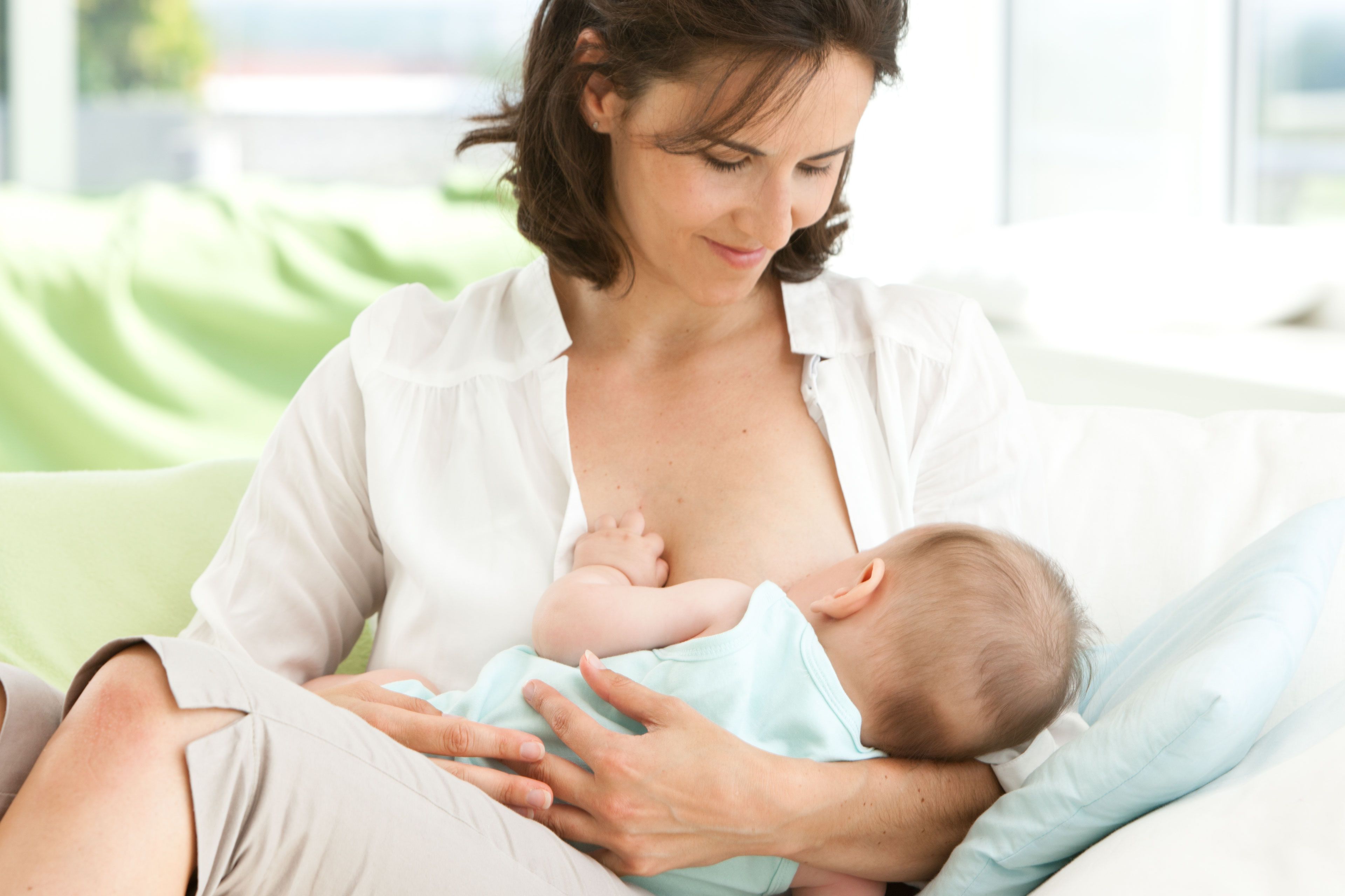 Eine Frau hält bequem ein Baby, das von ihr gestillt wird.