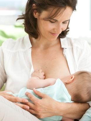 Eine Frau hält bequem ein Baby, das von ihr gestillt wird.