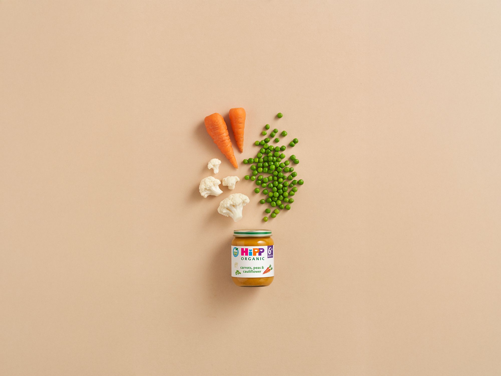 HiPP Organic Carrots, Peas & Cauliflower baby food jar with fresh carrots, peas and cauliflower on a neutral background