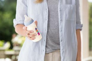 Mutter hält entspannt ein Fläschchen mit Babymilch in der Hand – Symbol für den sanften Übergang vom Stillen zur Flasche