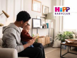 Mum and dad with baby reading a book in a living room
