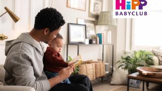 Mum and dad with baby reading a book in a living room
