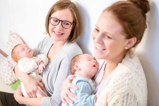 Zwei Frauen halten Babys, die beide zu schlafen scheinen.