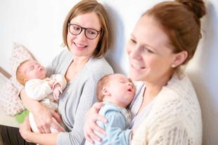 Zwei Frauen halten Babys, die beide zu schlafen scheinen.