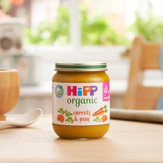 HiPP Organic Carrots & Peas on a dining table next to a bowl and spoon