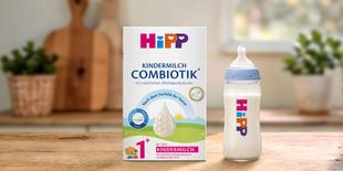 HiPP Kindermilch Combiotik® 1+ Packung mit gefüllter Babyflasche auf Holztisch in heller Küche