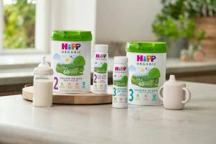 HiPP Organic Stage 2 Follow On Milk and Stage 3 Growing Up Milk tins and ready-to-feed bottles on a kitchen counter.
