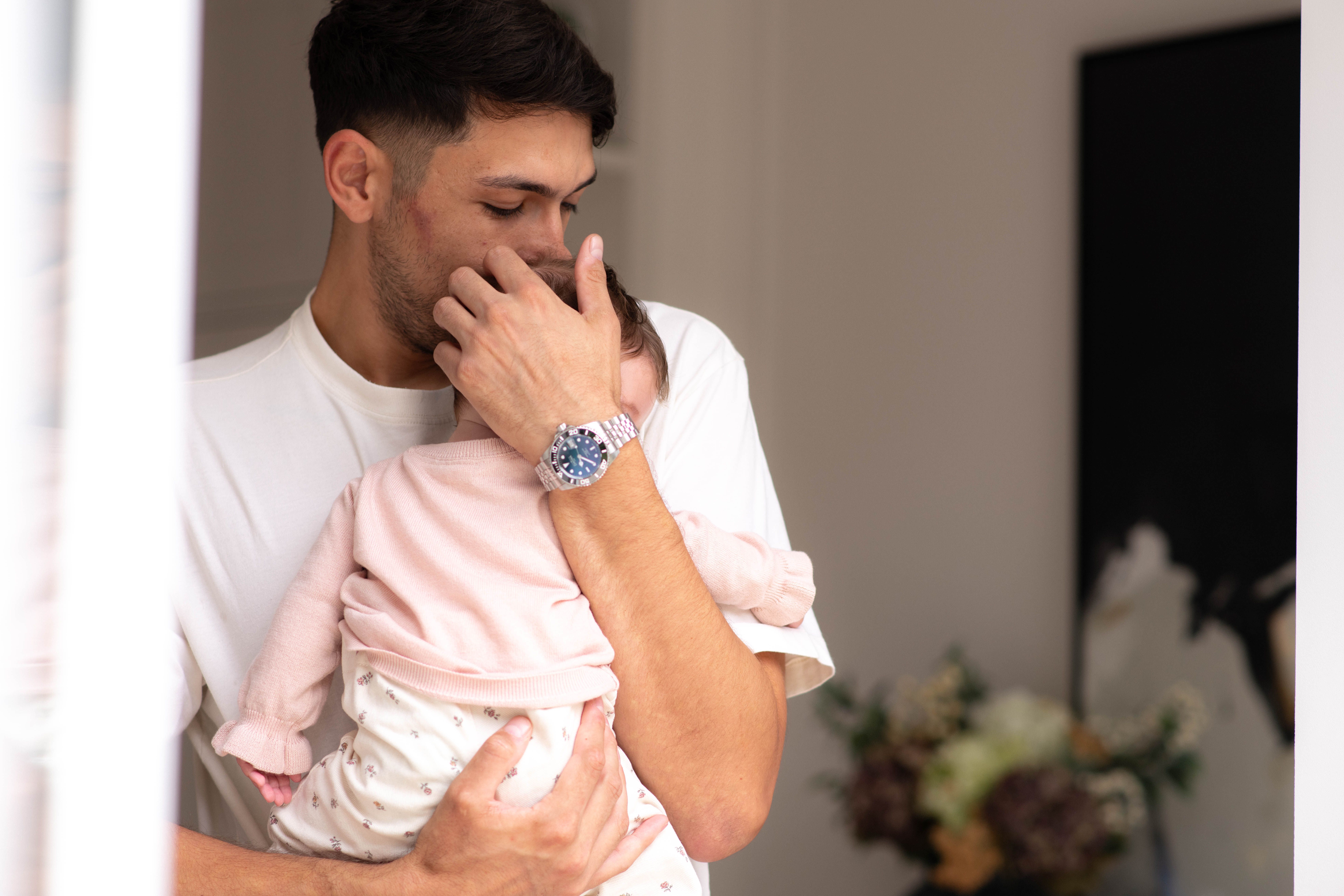 Parent gently cuddling a young baby on their shoulder, offering comfort during colic or constipation discomfort.