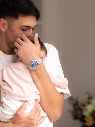 Parent gently cuddling a young baby on their shoulder, offering comfort during colic or constipation discomfort.