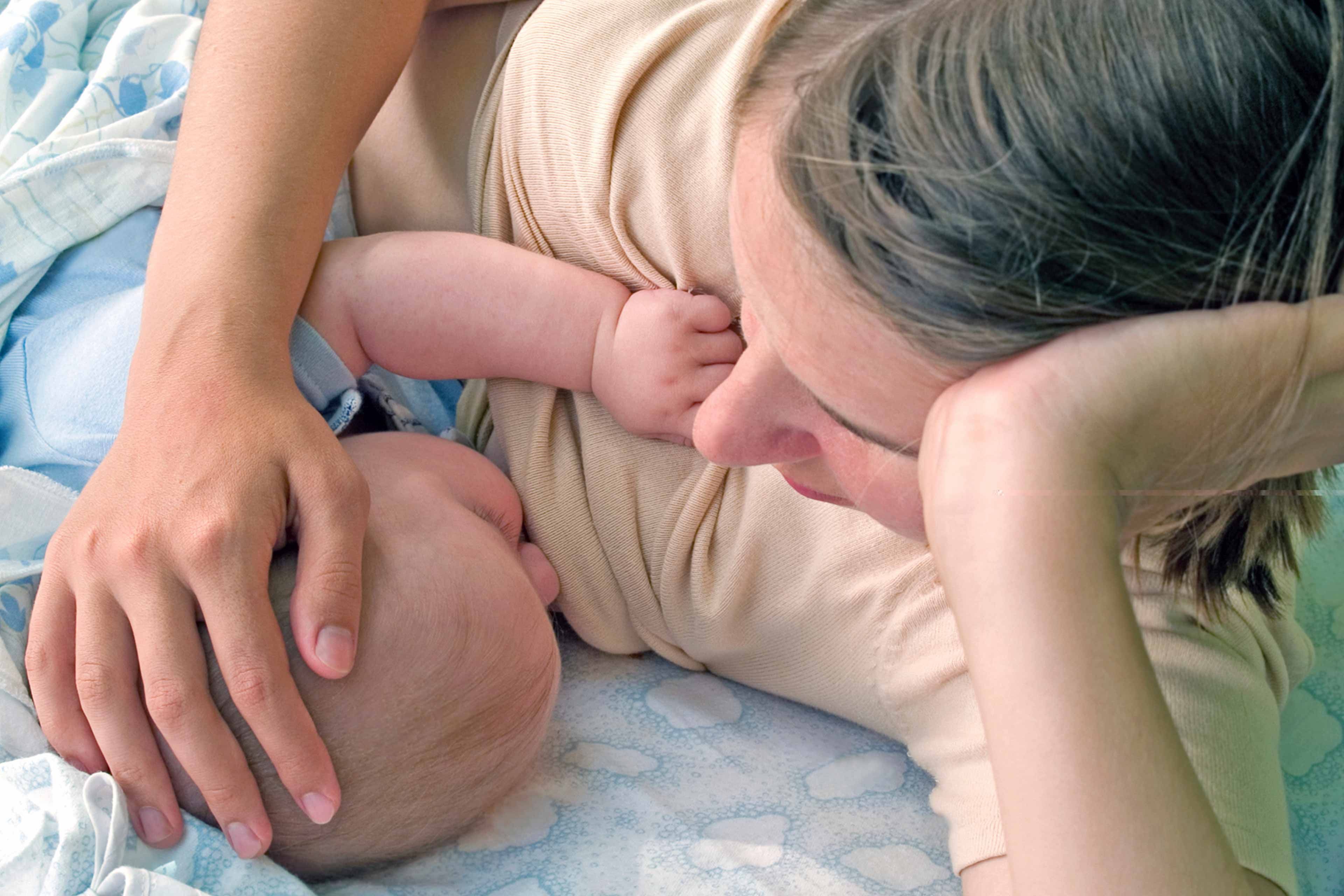 Die zärtliche Umarmung einer Mutter für ihr Baby, wobei die Hand der Mutter sanft auf dem Kopf des Babys ruht.