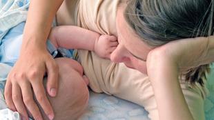Die zärtliche Umarmung einer Mutter für ihr Baby, wobei die Hand der Mutter sanft auf dem Kopf des Babys ruht.