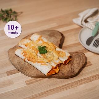 Baby-friendly veggie enchilada rolls on a wooden plate with cucumber sticks and a smooth green veggie dip.