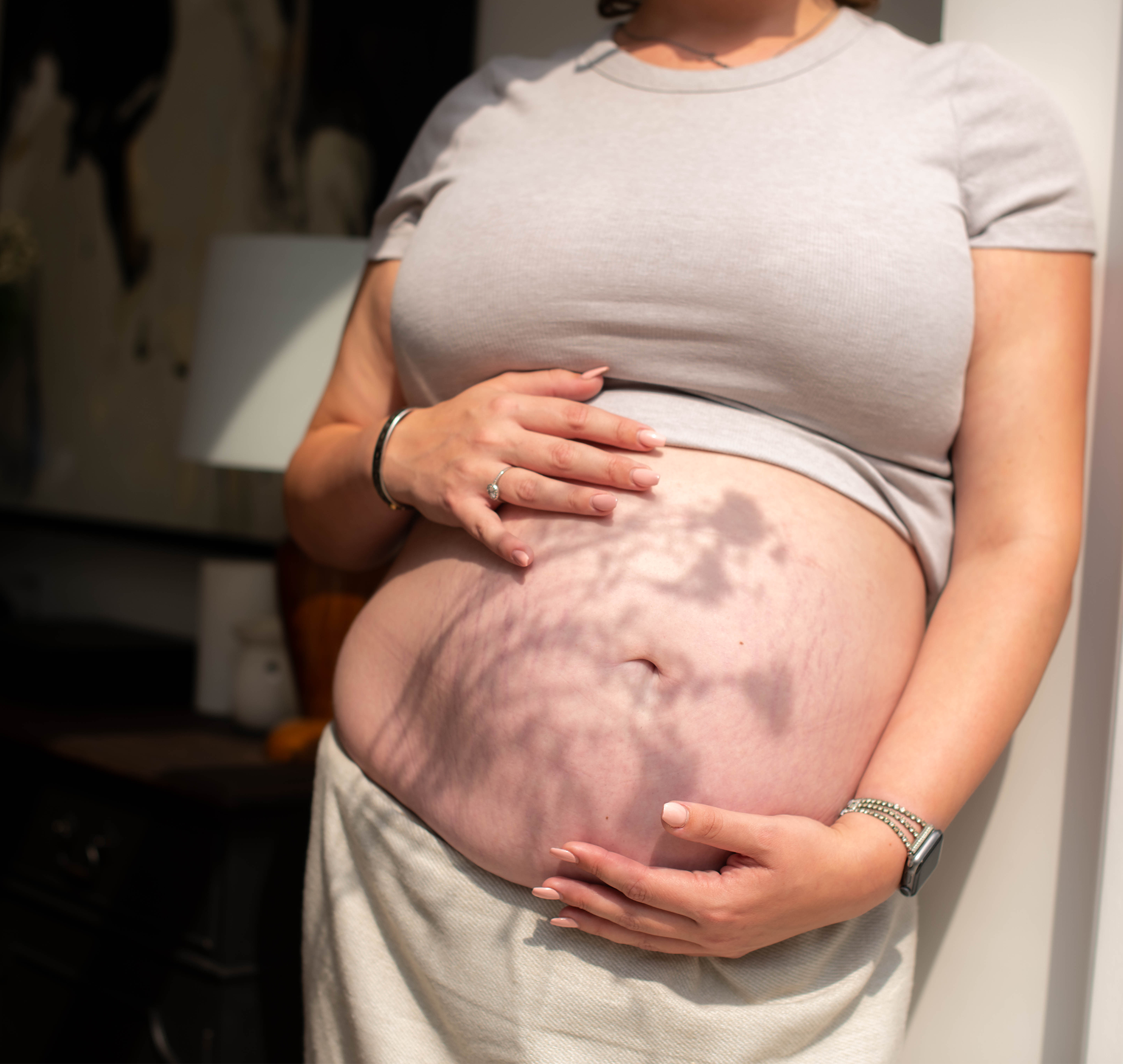 Close up of woman holding her bump with flower shadow across the image
