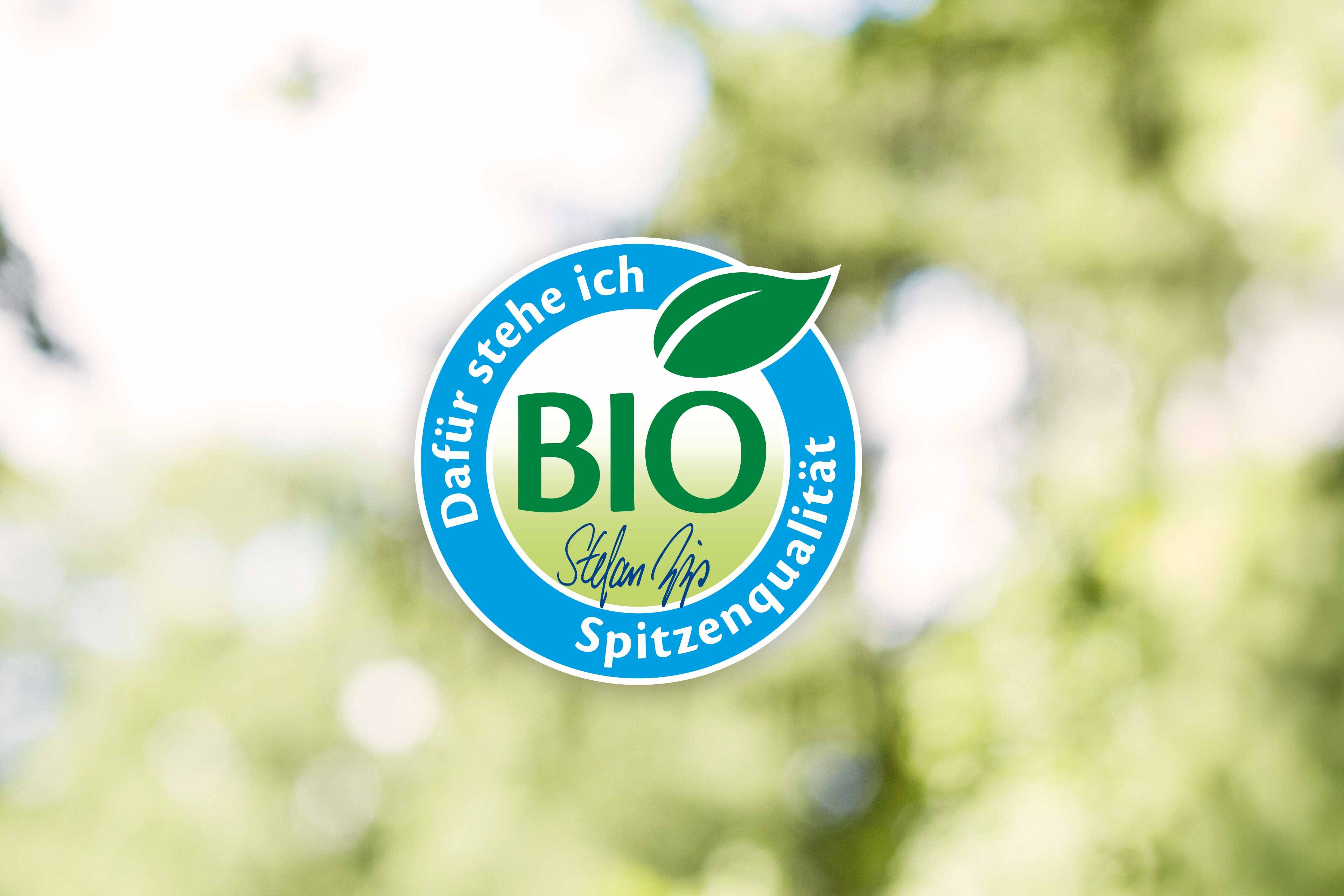 Ein blaues, kreisförmiges Logo mit dem Text "BIO" in der Mitte, umgeben von einem grünen Blatt und dem deutschen Text "Dafür stehe ich" oben und "Selten Qualität" unten.