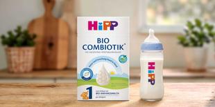 HiPP 1 BIO Combiotik® Anfangsmilch-Packung neben gefülltem HiPP-Babyfläschchen auf Holztisch in heller Küche