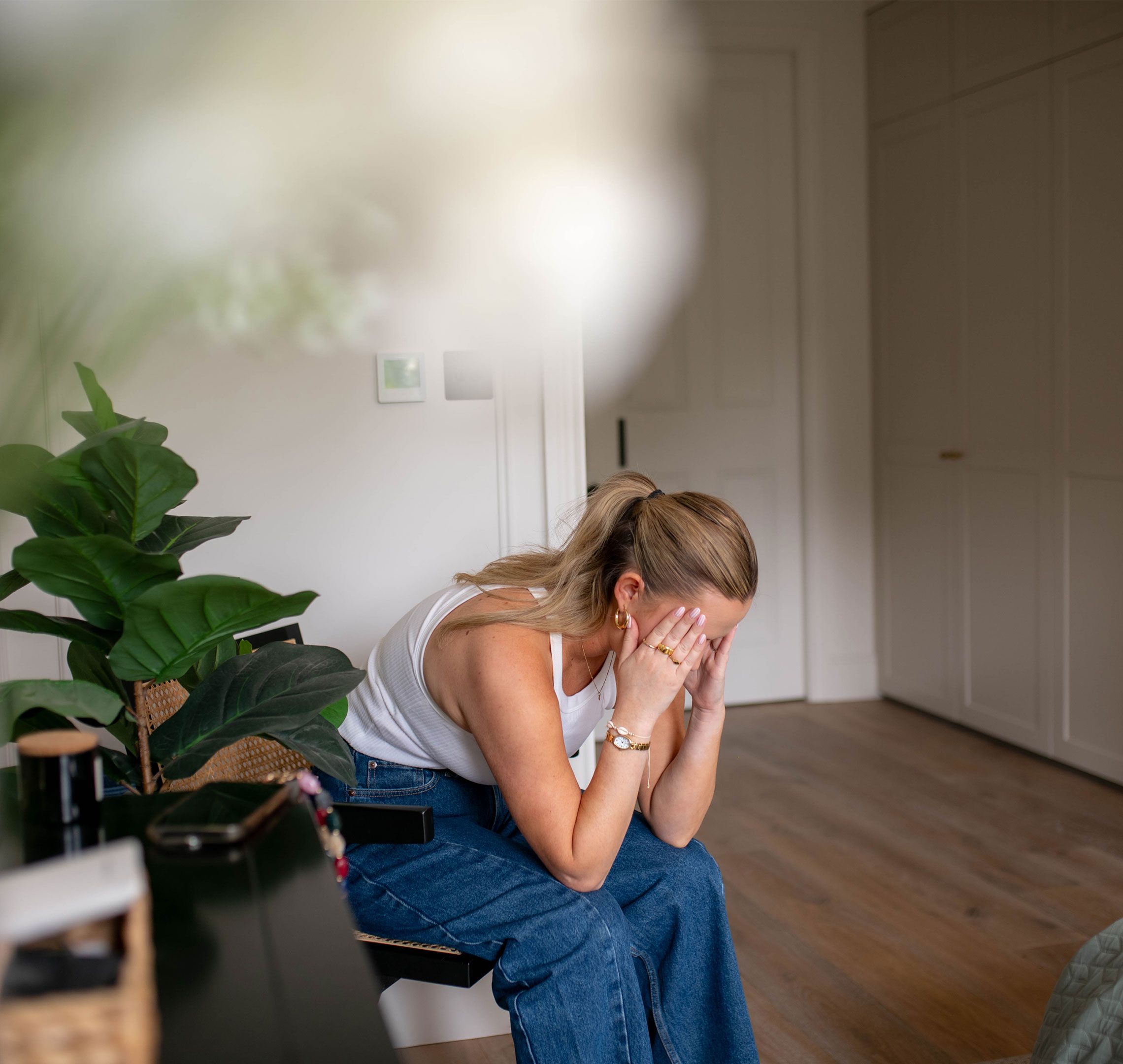 Pregnant woman sitting on a chair at home, head in hands, showing first trimester fatigue and overwhelm.