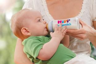 Ein Baby trinkt Milch aus einer Flasche mit der Aufschrift "Hipp", auf der der Name "Folgemilch" steht.