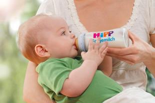 Ein Baby trinkt Milch aus einer Flasche mit der Aufschrift "Hipp", auf der der Name "Folgemilch" steht.
