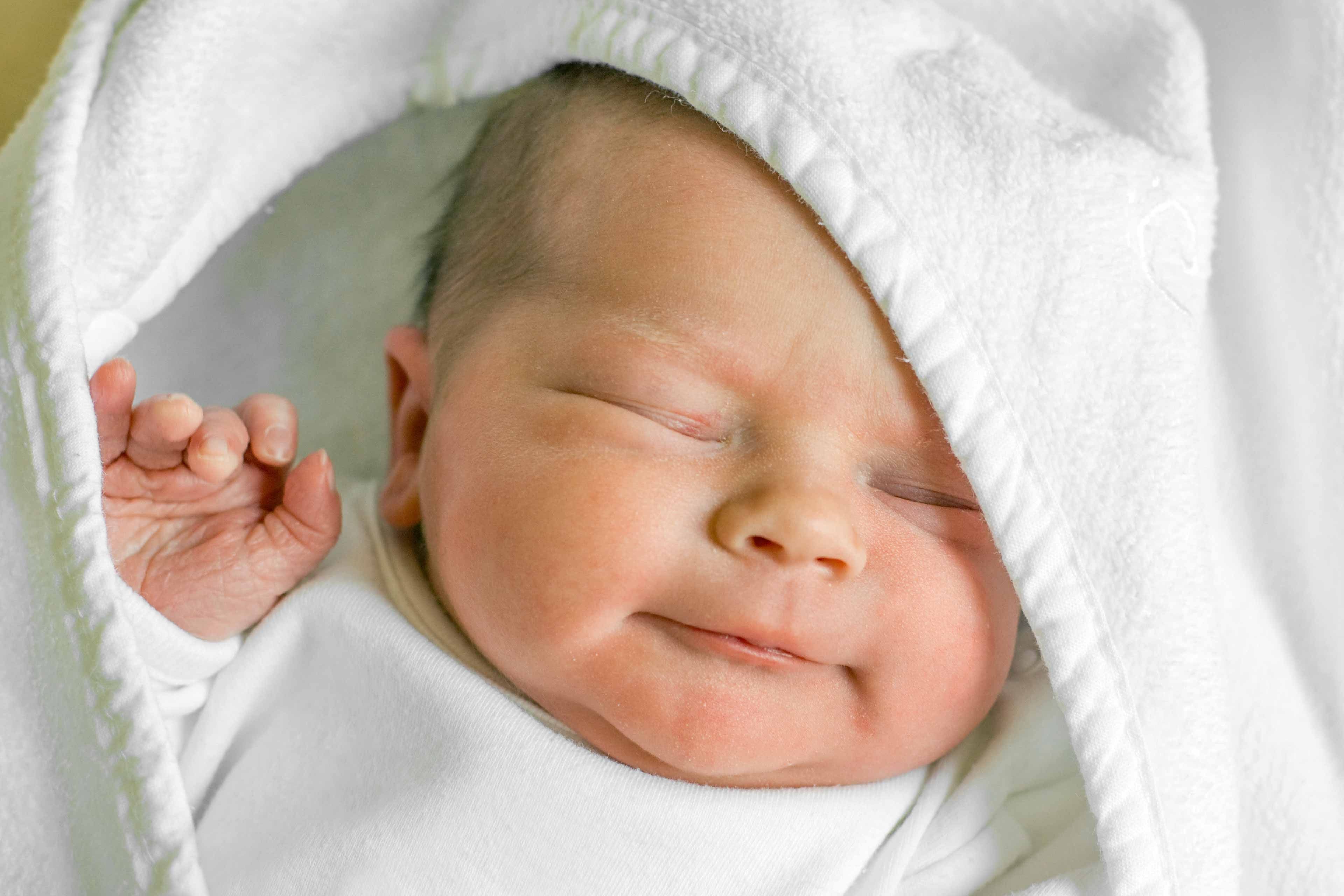 Ein lächelndes Babygesicht eingehüllt in eine Decke