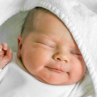 Ein lächelndes Babygesicht eingehüllt in eine Decke
