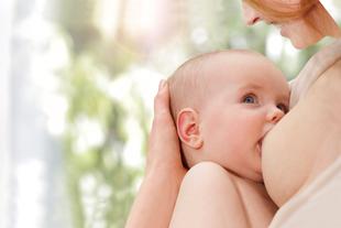 Gestilltes Baby liegt im Arm der Mutter und trinkt an der Brust, Symbol für natürliche Probiotika und Präbiotika in Muttermilch.