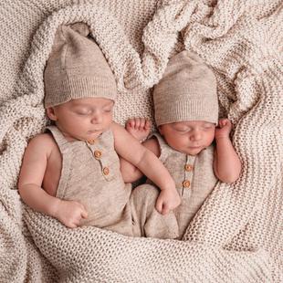 2 Babys mit Mütze liegen auf einer Decke