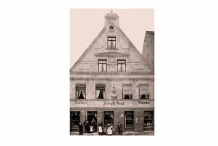 Historische Außenansicht des Café und der Konditorei Joseph Hipp in Pfaffenhofen mit Familie und Mitarbeitenden vor dem Eingang.