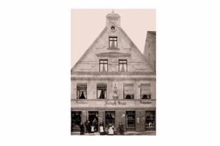 Historische Außenansicht des Café und der Konditorei Joseph Hipp in Pfaffenhofen mit Familie und Mitarbeitenden vor dem Eingang.