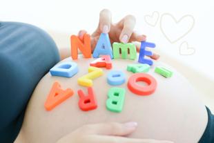 Eine Hand, die bunte Buchstaben des Alphabets auf einen schwangeren Bauch legt, wobei das Wort NAME deutlich zu lesen ist.