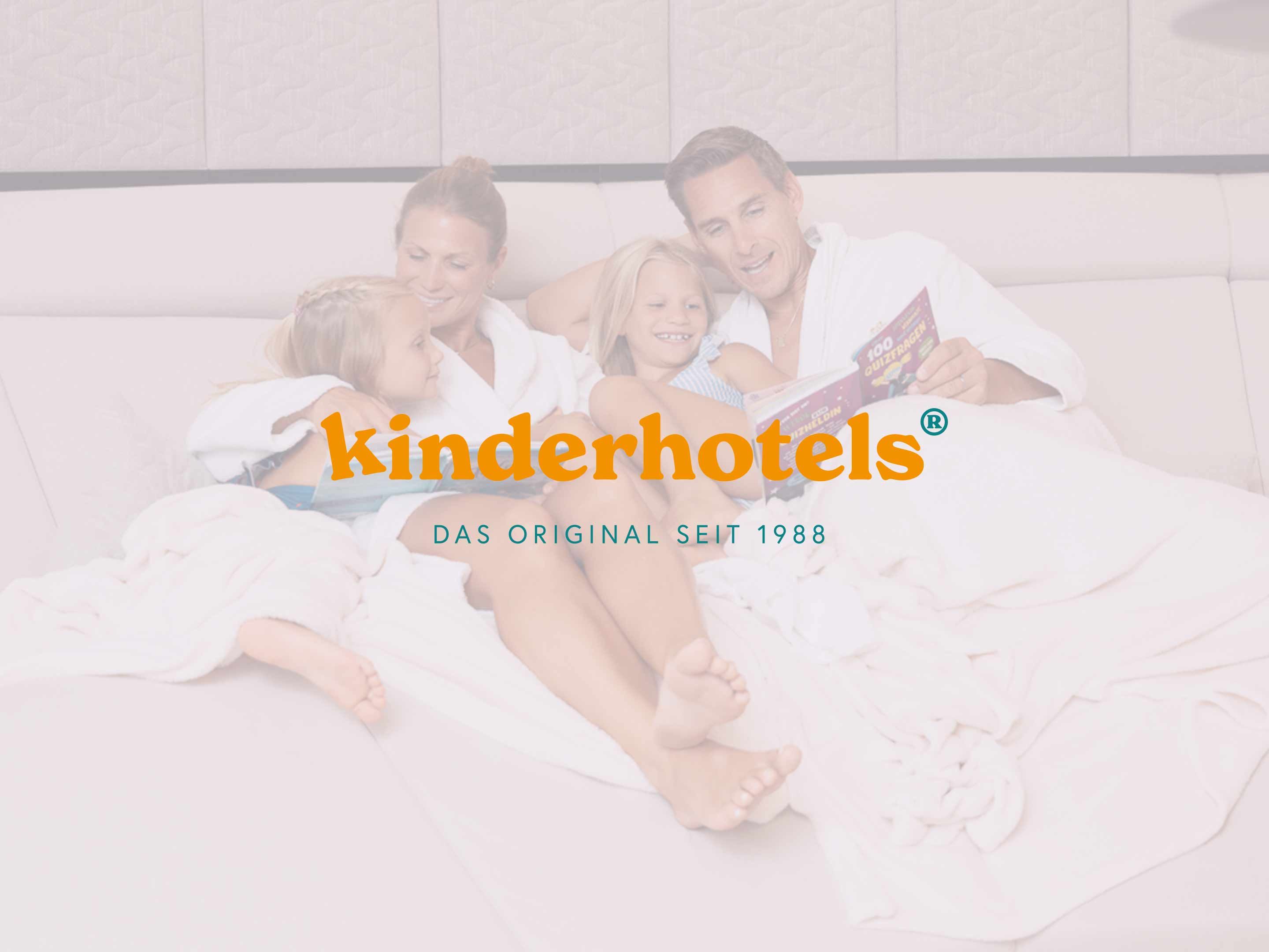 Familie mit zwei Kindern liegt entspannt auf einem großen Bett