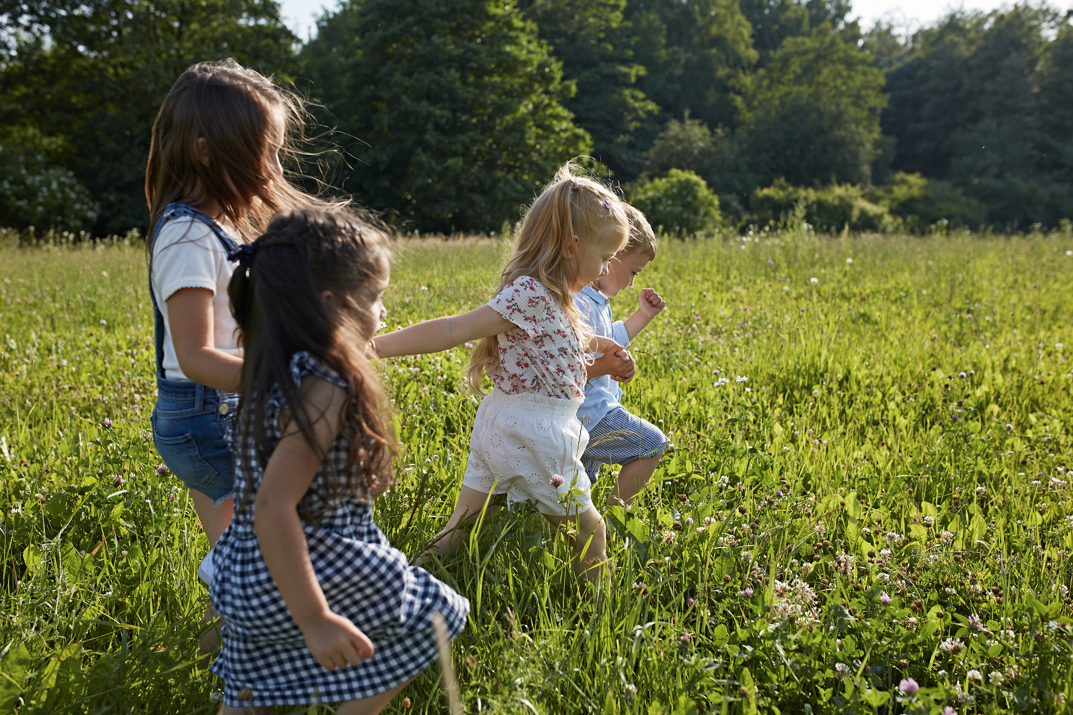Vier Kinder laufen auf einer Wiese