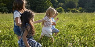 Vier Kinder laufen auf einer Wiese