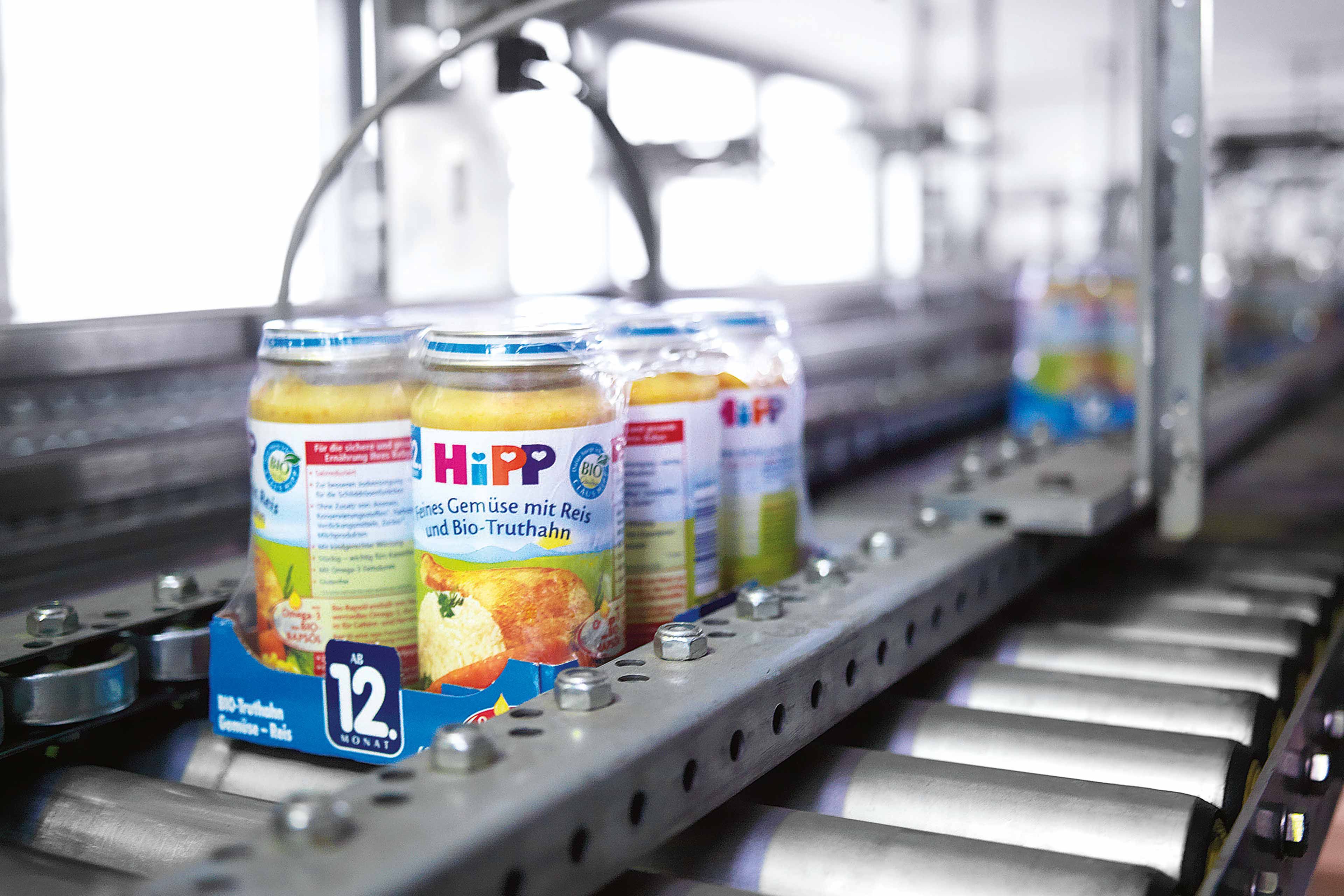 HiPP Bio-Gemüsegläschen auf einem Förderband in der Qualitätskontrolle im Werk