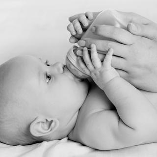 Eine Mutter, die ihr Baby mit der Flasche füttert, im Freien.