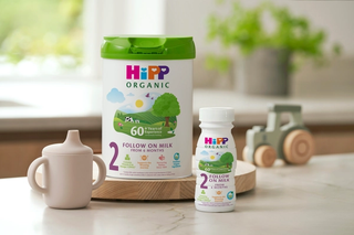 HiPP Organic follow on milk powder tin and ready to feed bottle on a kitchen worktop next to a baby bottle of milk