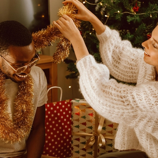 Expecting couple wrapping tinsel around each others neck