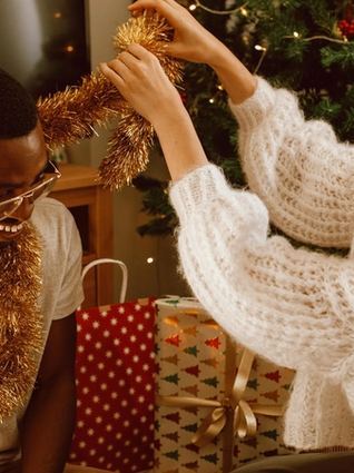 Expecting couple wrapping tinsel around each others neck