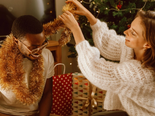 Expecting couple wrapping tinsel around each others neck