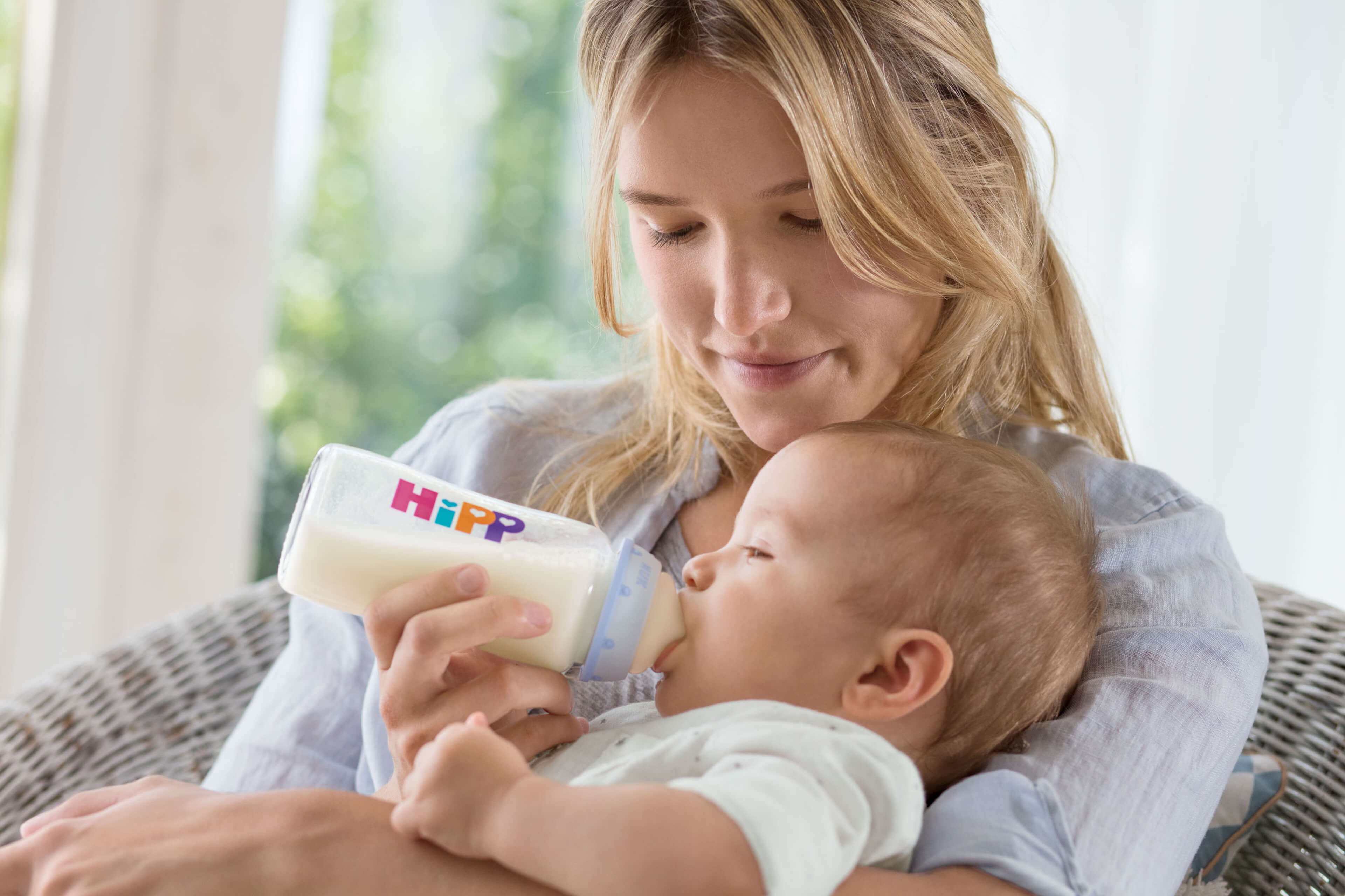 Eine Frau füttert ihr Baby mit einer Hipp-Flasche.
