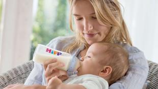 Eine Frau füttert ihr Baby mit einer Hipp-Flasche.