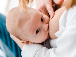 Nahaufnahme eines Babys, das an der Brust einer Person liegt
